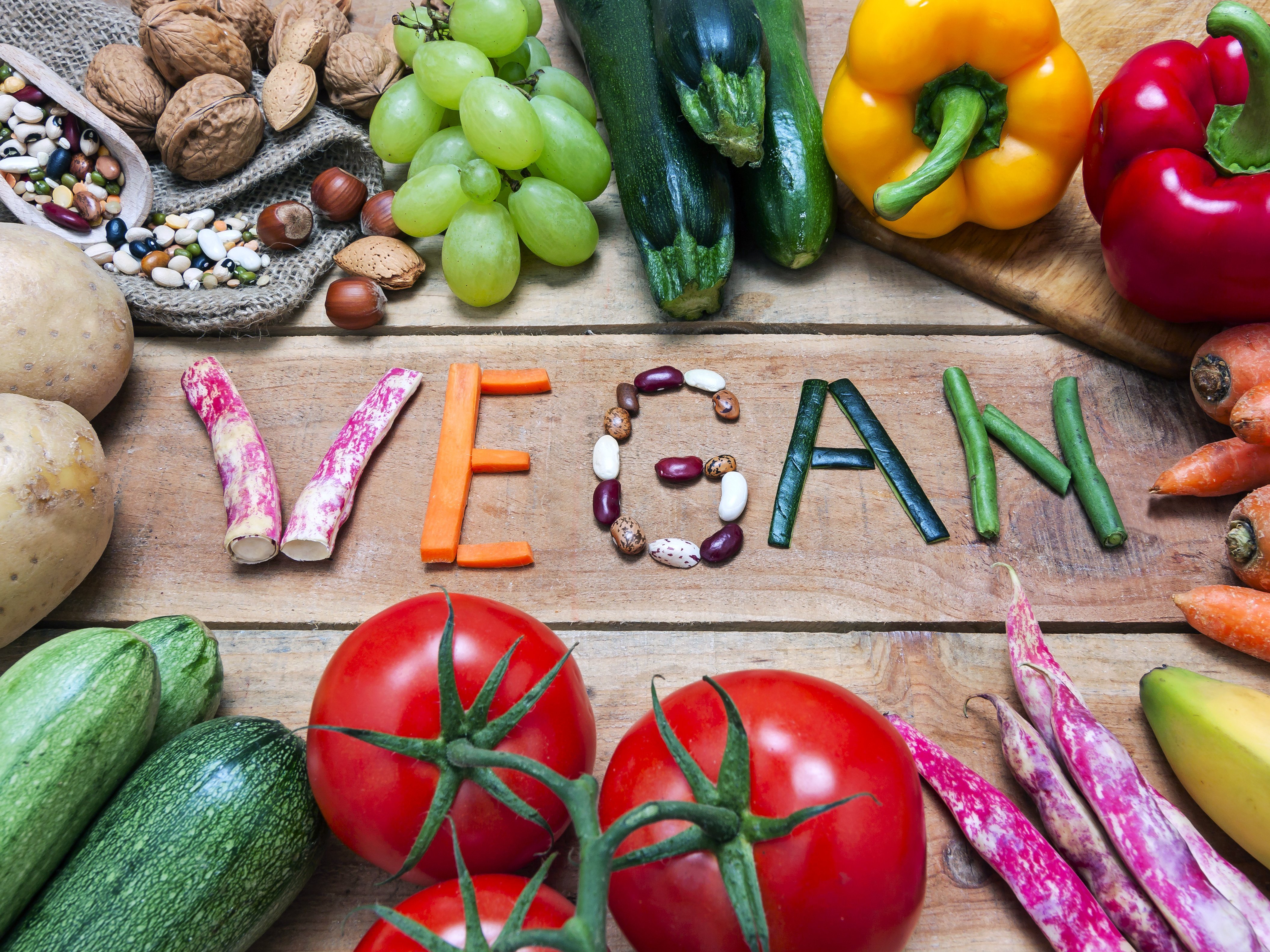 Buffet von diversem Obst und Gemüse mit Vegan-Schriftzug aus Bohnen, Karotten & Co