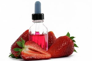 4 Stück Erdbeeren umgeben eine rote Flasche mit Pipette und roter Flüssigkeit