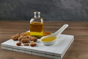 Erdnussöl-Flasche, Erdnüsse und Löffel mit Erdnussöl